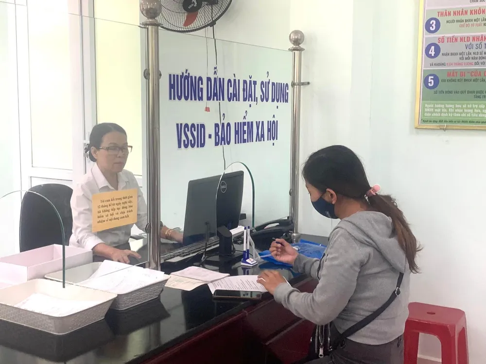 Người lao động và đại diện các đơn vị sử dụng lao động làm thủ tục BHXH. Ảnh: VĂN PHÚC