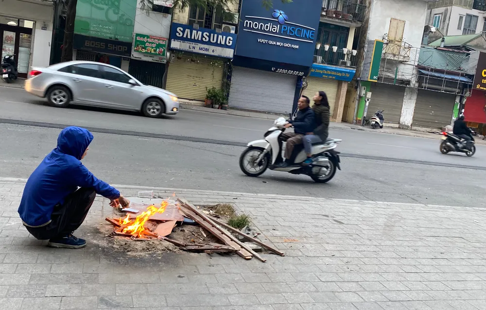 Một tài xế đốt lửa sưởi trên vỉa hè Kim Mã (Hà Nội). Ban ngày đã có nắng ấm nhưng sáng sớm trời vẫn rét buốt. Ảnh: PHÚC VĂN IMG_6028.jpeg