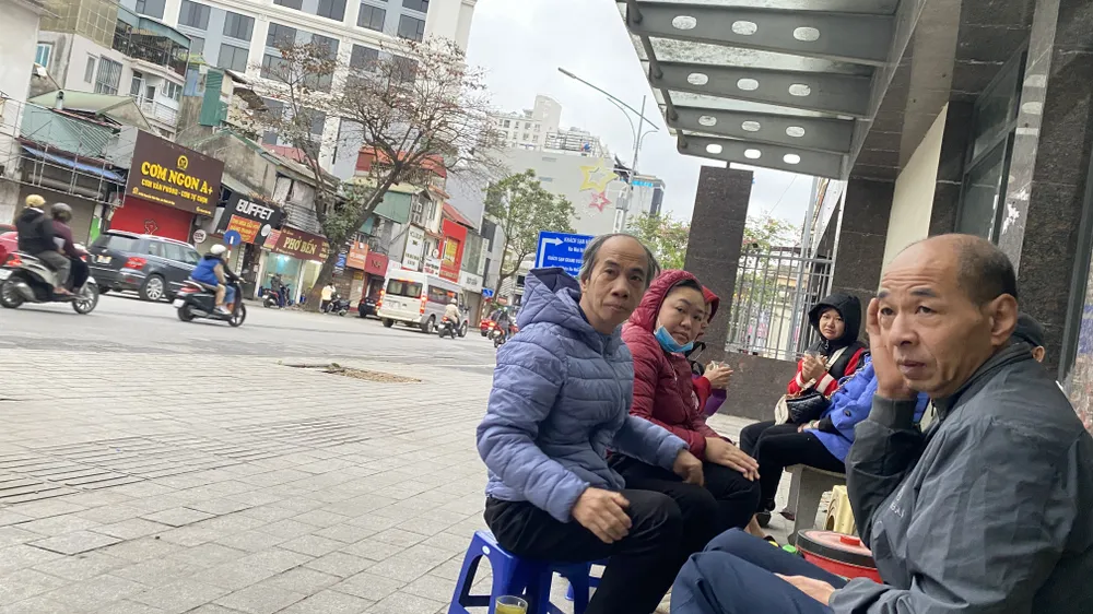 Người dân Hà Nội ngồi chờ xe buýt tại một quán nước chè nóng ven đường, sáng 3-2. Ảnh: PHÚC HẬU IMG_6975.jpeg