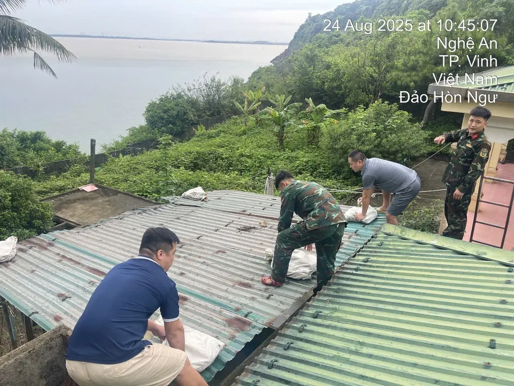 Cán bộ khí tượng cùng các chiến sĩ đặt các bao cát bảo vệ mái nhà của Trạm Khí tượng Hòn Ngư trước trận cuồng phong. Ảnh: HOÀNG LINH IMG_1695.jpeg