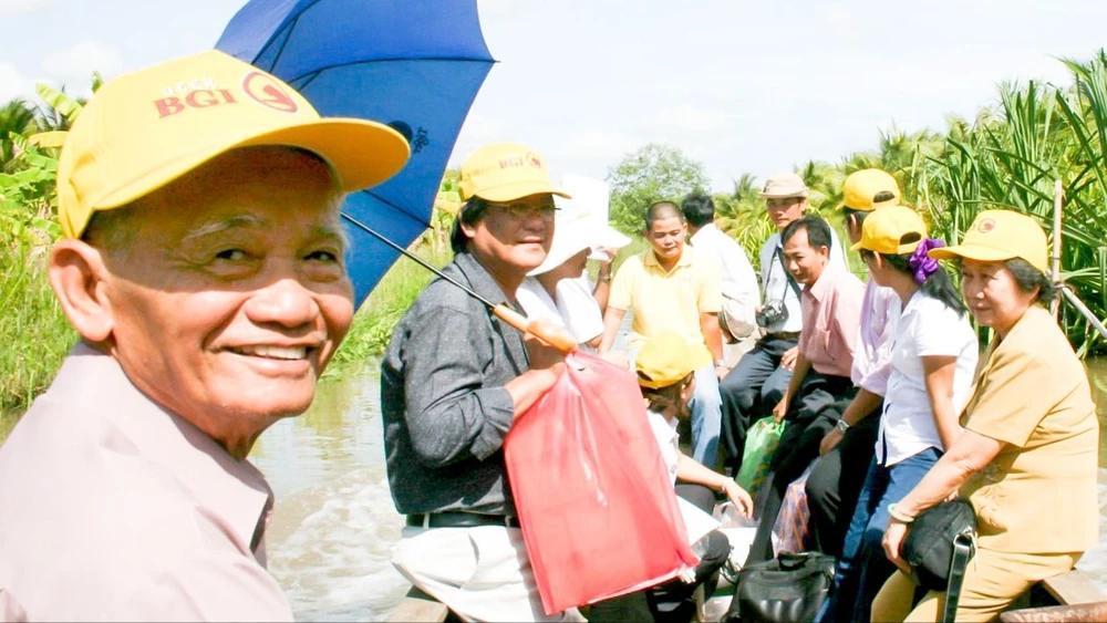 Anh Lê Minh Châu (bìa trái) đi xuồng vào thăm gia đình Anh hùng liệt sĩ Trần Thị Anh, năm 2010