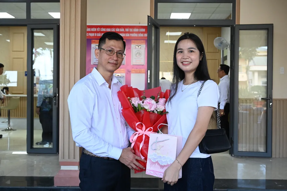 Đại diện lãnh đạo phường Đồng Xoài (bên phải) tặng hoa và quà cho công dân đến giải quyết thủ tục hành chính - 2.jpg