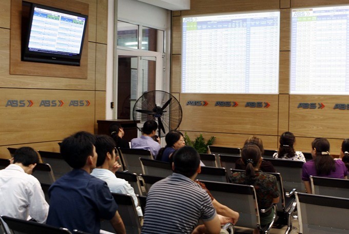 Investors watch share prices on electronic boards at An Binh Securities Co. (Photo: VNS)