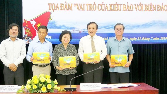 Mr. Hoang Chi Hung (L), chairman of the Press Photo Club under HCMC Journalists Association gives delegates at the seminar photobooks on sea and islands (Photo: SGGP)