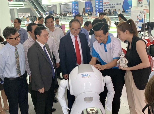 HCMC leaders look at AI products displayed at an exhibition held on the "Day for AI and IT Enterprises" event recently in HCMC. (Photo: VNA/VNS)