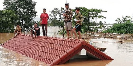 Người dân đứng trên nóc nhà chờ giải cứu khi nước lũ dâng cao do vỡ đập