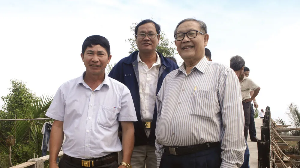 Ông Trịnh Văn Y (bên phải) đi kiểm tra một cây cầu sắp hoàn thành