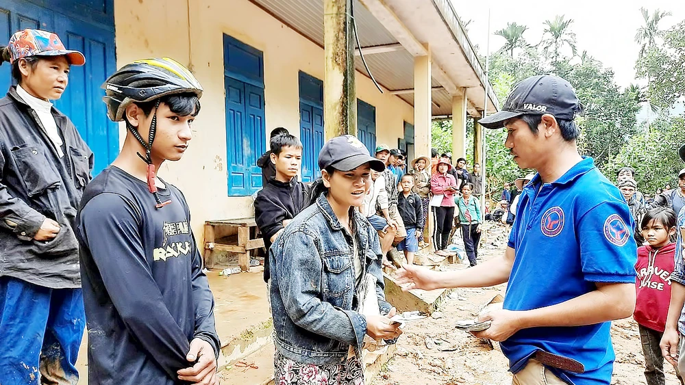 Thầy giáo Nguyễn Trần Vỹ (bìa phải) trao tặng tiền hỗ trợ bà con xã Trà Leng, Quảng Nam, bị bão số 9 làm hư hại tài sản