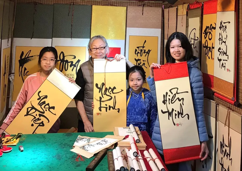 Nghệ sĩ thư pháp Huỳnh Mỹ Lý với các bạn trẻ đến xin chữ đầu năm. Ảnh: MAI AN Nghệ sĩ thư pháp Huỳnh Mỹ Lý với các bạn trẻ đến xin chữ đầu năm. Ảnh: MAI AN