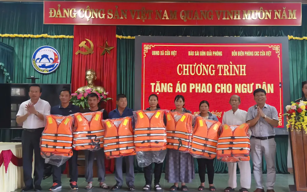 Phóng viên Báo SGGP và đại diện chính quyền địa phương trao áo phao cứu sinh tặng bà con ngư dân xã Cửa Việt, tỉnh Quảng Trị.