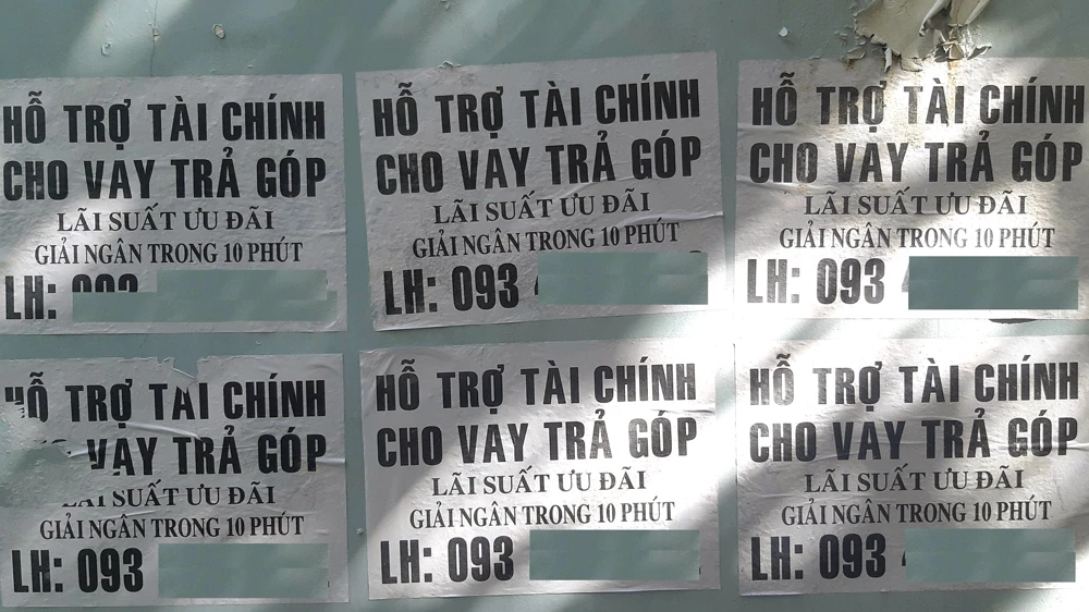 Tờ rơi quảng cáo cho vay tín dụng đen dán đầy các cột điện, bờ tường để giăng bẫy người nghèo. Ảnh: ĐỨC TRUNG