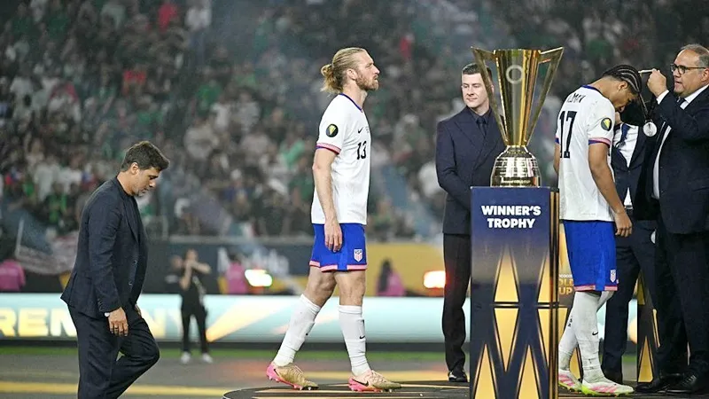 HLV Maurico Pochettino và các cầu thủ Mỹ lầm lũi bước qua chiếc Cúp Vàng.