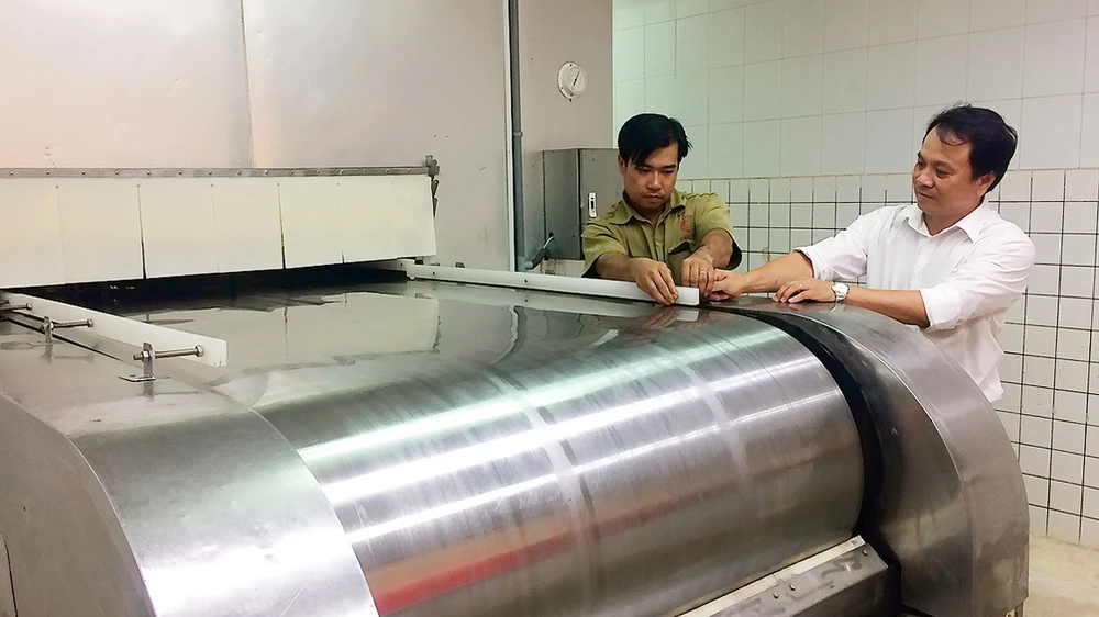 Anh Nguyễn Thanh Hiền (phải) cùng đồng nghiệp bên băng chuyền cấp đông IQF do anh cải tạo