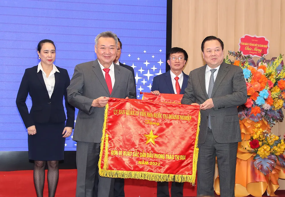 Đồng chí Phạm Quốc Bảo (bên trái) nhận cờ Đơn vị xuất sắc dẫn đầu phong trào thi đua năm 2022 do Ủy ban Quản lý vốn nhà nước tại doanh nghiệp tặng