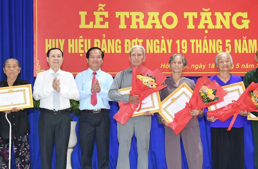 Phó Bí thư Thành ủy TPHCM Nguyễn Văn Hiếu cùng Bí thư Huyện ủy huyện Hóc Môn Trần Văn Khuyên trao Huy hiệu Đảng cho các đảng viên cao tuổi Đảng. Ảnh: VIỆT DŨNG