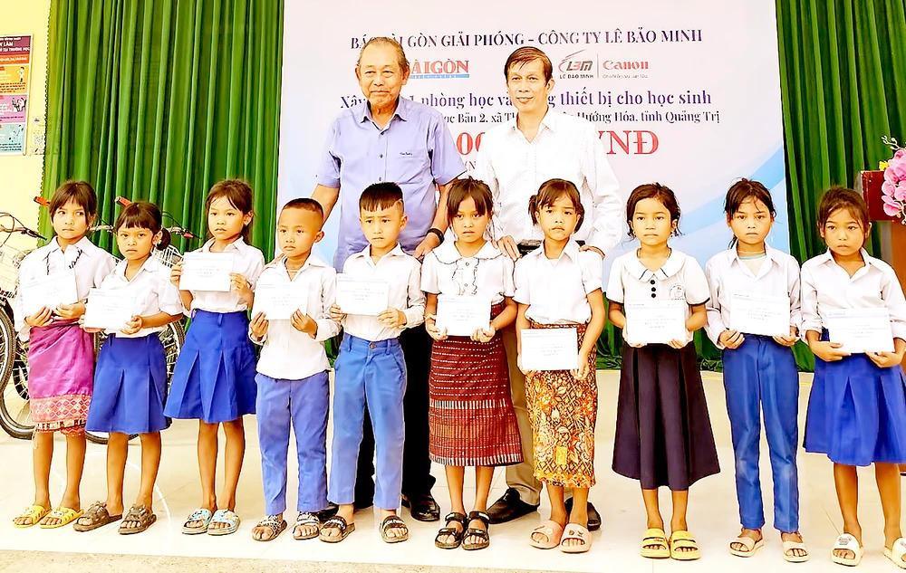 Nguyên Phó Thủ tướng Thường trực Trương Hòa Bình và Phó Tổng biên tập Báo SGGP Nguyễn Khắc Văn trao học bổng Báo SGGP tặng học sinh nghèo vượt khó ở Trường Tiểu học Thuận, huyện Hướng Hóa, tỉnh Quảng Trị