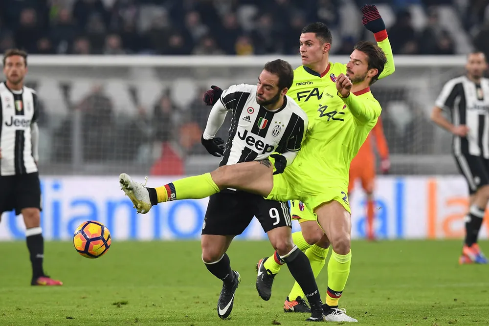 Gonzalo Higuain (trái, Juventus) tranh bóng với hậu vệ Bologna.