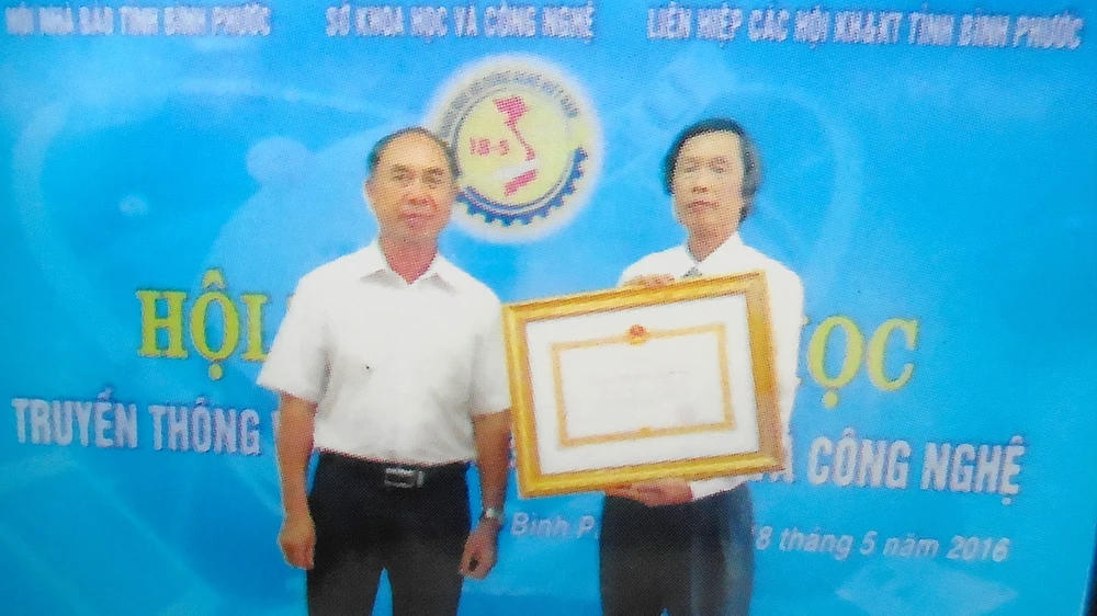 Ông Trần Văn Vân (phải) nhận Huân chương Lao động hạng hai tặng thưởng Sở KH-CN tỉnh Bình Phước