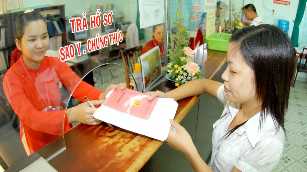 Nhân viên UBND phường Hiệp Bình Chánh (mặc áo dài) giải quyết hồ sơ cho người dân. Ảnh: KIM NGÂN