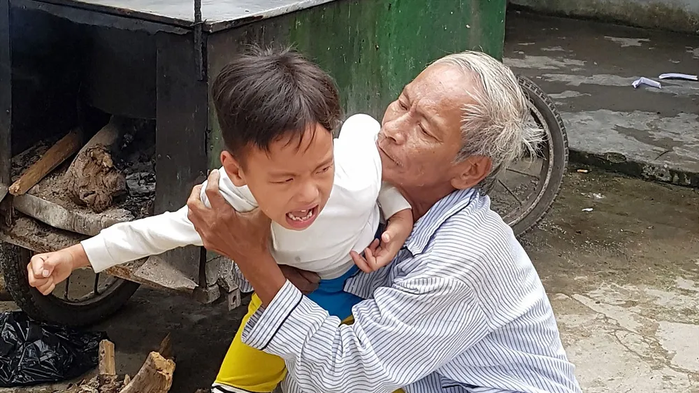 Ông Chinh đang dỗ dành đứa cháu nội tật nguyền