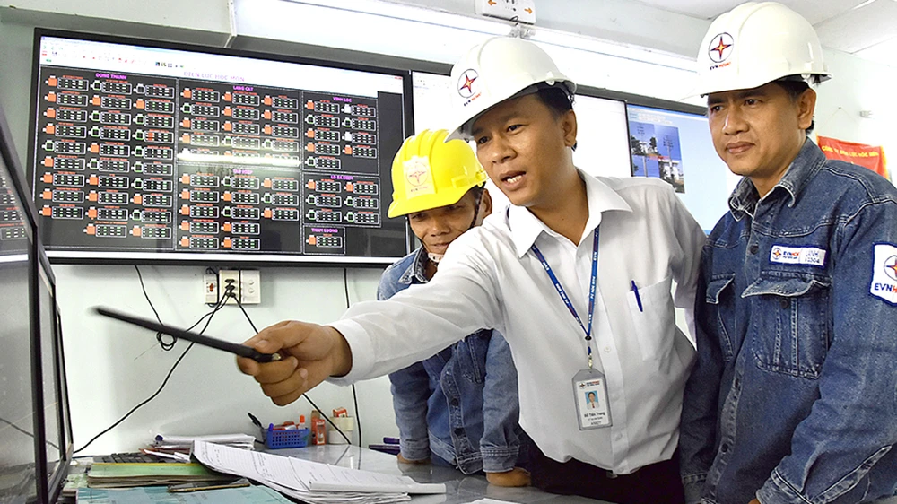 Kỹ sư Đỗ Tiến Trung (giữa) và đồng nghiệp giám sát hệ thống lưới điện tại Trung tâm quản lý lưới điện Hóc Môn