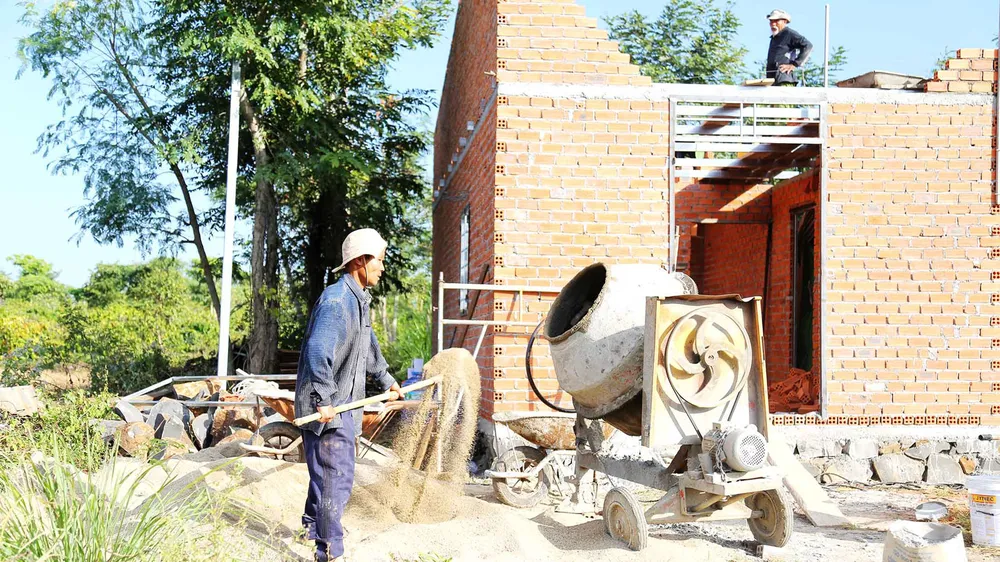 Anh Trần Ngọc Tài (huyện Cư Mgar, tỉnh Đắk Lắk) bên căn nhà đang được xây mới từ “Quỹ tiết kiệm 1.000 đồng”