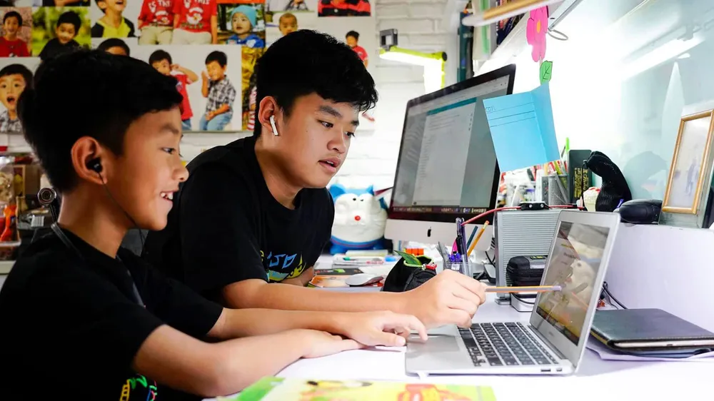 Em Nguyễn Huỳnh Thông, lớp 3 trường Võ Thị Sáu đang làm quen với cách học trực tuyến với sự hướng dẫn của người anh Nguyễn Huỳnh Bách, lớp 7 trường Đinh Thiện Lý. Ảnh: THANH TÙNG