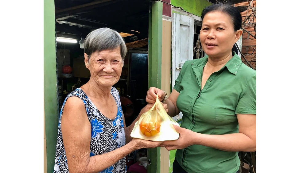 Chị Huỳnh Thị Phẩm mang bữa ăn đến tận nhà cho bà Lê Thị Mai 