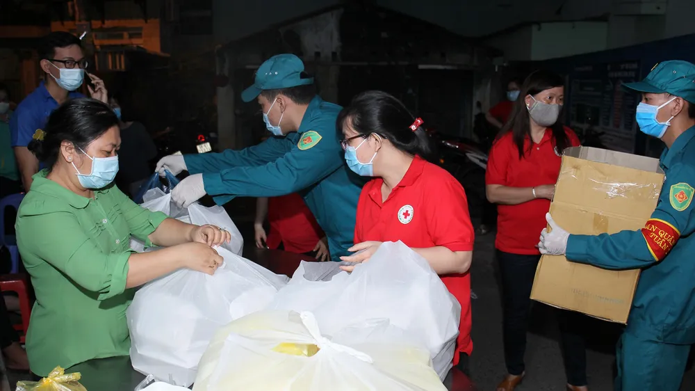 Các chiến sĩ dân phòng hỗ trợ tiếp tế cho bà con đang cách ly tại khu Bình Tiên - Phạm Phú Thứ, quận 6. Ảnh: HOÀNG HÙNG