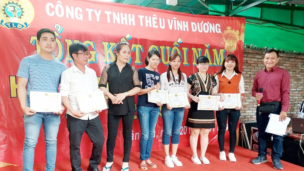  Anh Liêu Ngọc Sơn (bìa phải), Bí thư Chi bộ, Chủ tịch Công đoàn Công ty TNHH thêu Vĩnh Dương (quận Tân Phú, TPHCM) trao giấy khen cho đoàn viên có thành tích tốt trong sản xuất