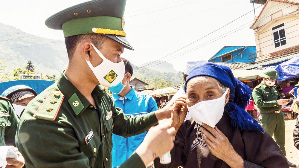  Các chiến sĩ Đồn Biên phòng Y Tý phát và hướng dẫn đồng bào các dân tộc đeo khẩu trang, phòng dịch Covid-19. Ảnh: ĐBP