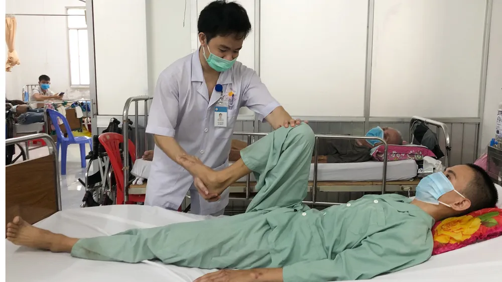 Anh Lục Rồi Hỷ (22 tuổi) được kỹ thuật viên hỗ trợ tập vật lý trị liệu, phục hồi chức năng