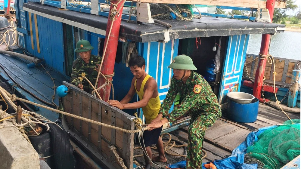 Bộ đội Biên phòng Hà Tĩnh giúp ngư dân chằng chống tàu để tránh bão. Ảnh: DƯƠNG QUANG