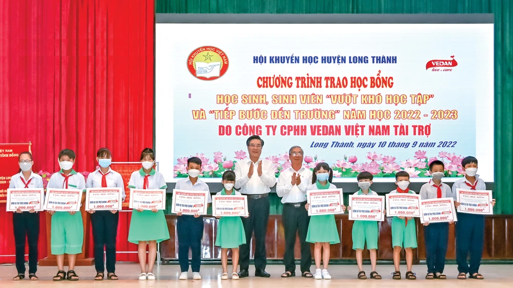 Ông Dương Minh Dũng - Ủy viên TVTU, Bí thư huyện Long Thành (trái) ông Lê Minh Hoàng - Phó chủ tịch Hội khuyến học tỉnh Đổng Nai (phải) trao học bổng cho các em học sinh