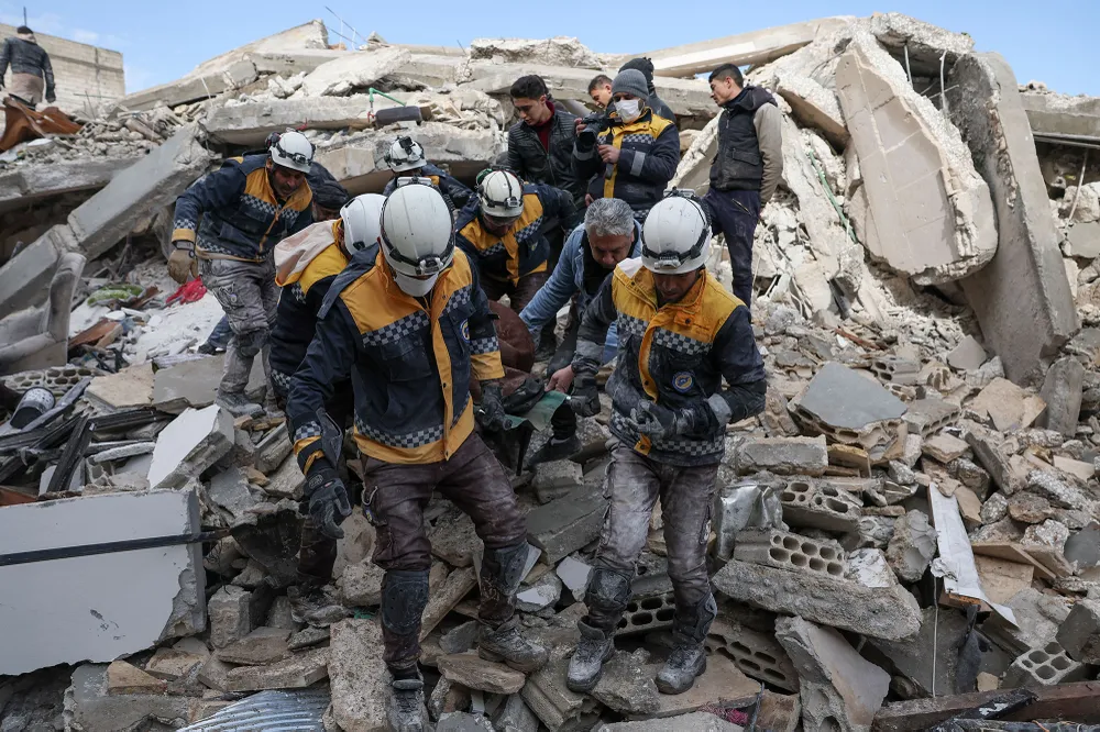 Các thành viên Lực lượng Phòng vệ dân sự Syria, vận chuyển một nạn nhân từ đống đổ nát của các tòa nhà ở làng Azmarin thuộc tỉnh Idlib phía Tây Bắc Syria do quân nổi dậy nắm giữ vào ngày 7- 2 Các thành viên Lực lượng Phòng vệ dân sự Syria, vận chuyển một nạn nhân từ đống đổ nát của các tòa nhà ở làng Azmarin thuộc tỉnh Idlib phía Tây Bắc Syria do quân nổi dậy nắm giữ vào ngày 7- 2