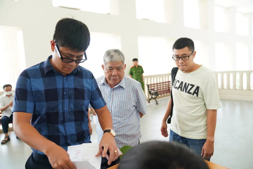 Ông Lê Thanh Thản đến dự phiên tòa được người thân dìu hai bên