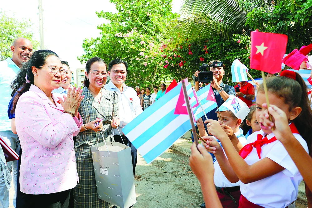 Các em học sinh làng Bến Tre đón đoàn đại biểu TPHCM đến thăm. Ảnh: NGÔ BÌNH 