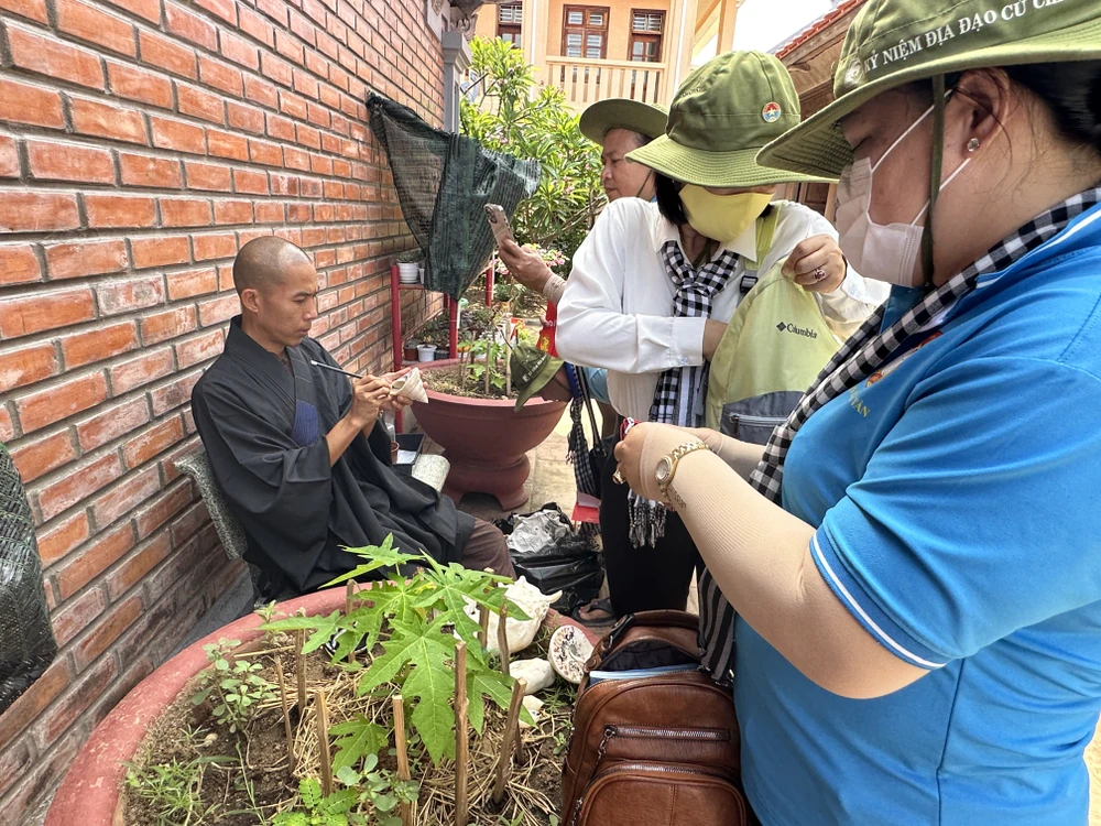 Đại đức Thích Nhuận Hiếu viết chữ lên vỏ ốc làm quà tặng cho khách từ đất liền ghé thăm chùa