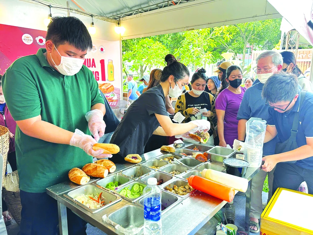 Người dân, du khách xếp hàng đợi mua và thưởng thức bánh mì Ảnh: QUỐC EM