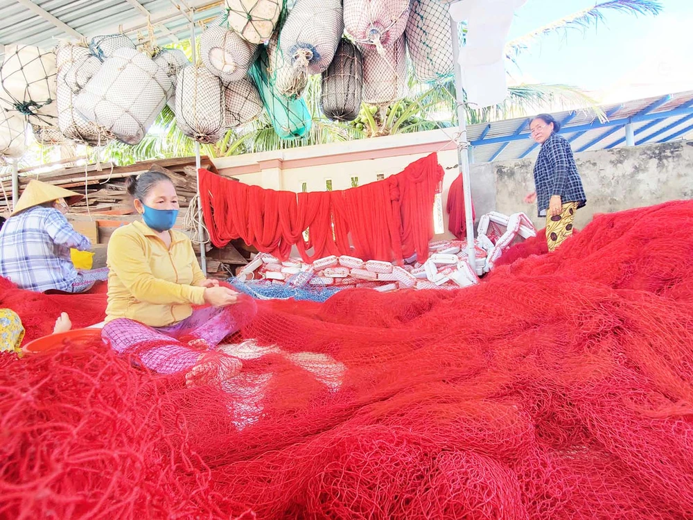 May vá, khâu nối những tấm lưới cá loại lớn chuẩn bị vươn khơi. Ảnh: NGỌC OAI PS17.jpg