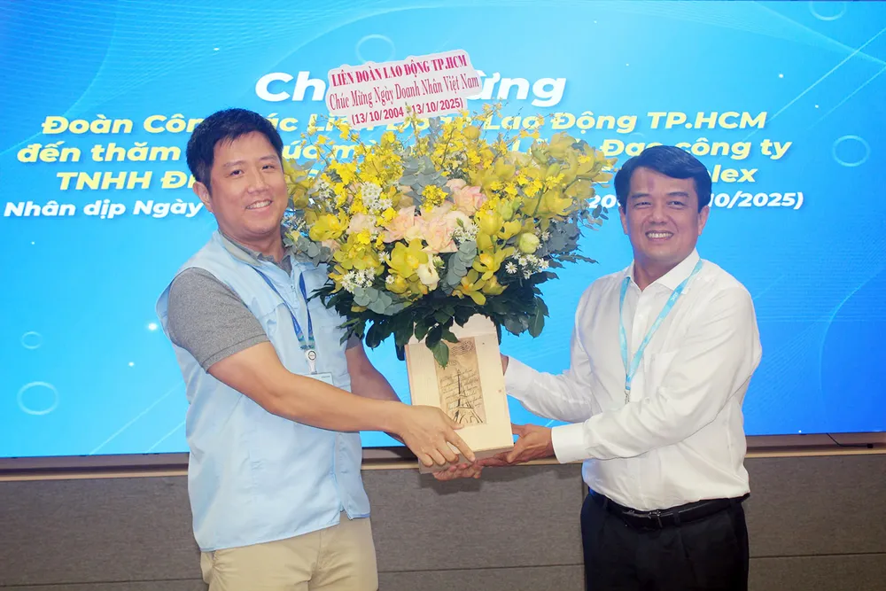 Đồng chí Bùi Thanh Nhân (bìa phải) tặng hoa đến đại diện lãnh đạo Công ty TNHH Điện tử Samsung HCMC CE Complex