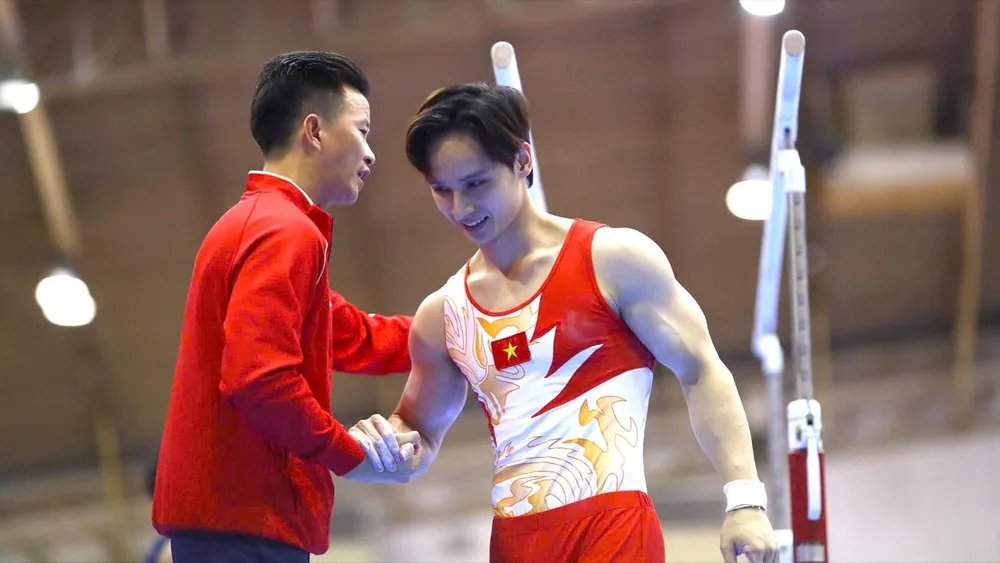 HLV Trương Minh Sang chúc mừng Đinh Phương Thành sau bài thi xà đơn. Ảnh: DŨNG PHƯƠNG