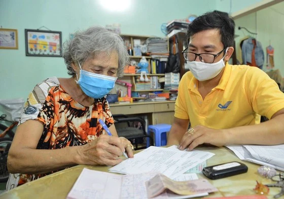 Nhân viên Bưu điện TPHCM tới tận nhà chi trả lương hưu, trợ cấp bảo hiểm xã hội tới người dân trên địa bàn TPHCM. Ảnh: VIỆT DŨNG