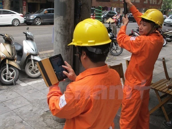 Nhân viên EVN áp dụng công nghệ trong việc ghi chỉ số côngtơ điện. (Ảnh: Xuân Quảng/Vietnam+)