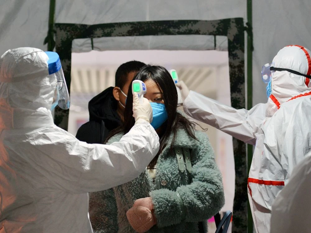 A government worker checks the travelers' body temperature at a railway station in Fuyang, China on Jan. 29. Photographer: Feature China/Barcroft Media via Getty Images