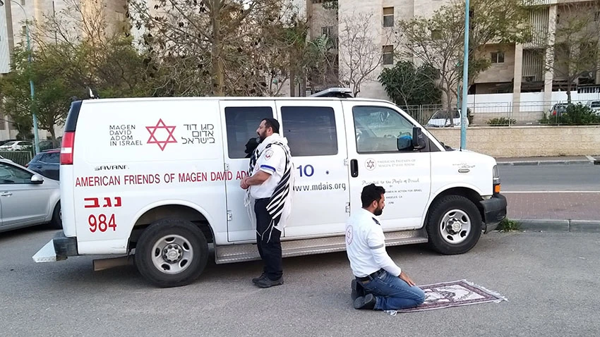 Jewish and Muslim paramedics with Israel's Magen David Adom emergency service pray together during the coronavirus outbreak. © Reuters