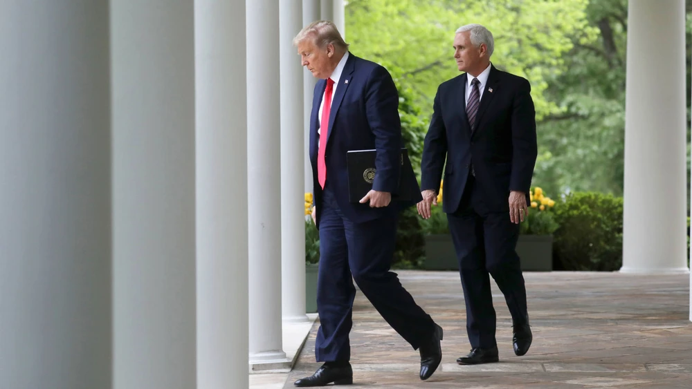 U.S. President Donald Trump walks down the West Wing colonnade from the Oval Office with Vice President Mike Pence as they arrive to address the daily coronavirus task force briefing in the Rose Garden at the White House on April 14. © Reuters