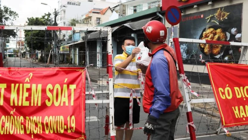 FILE PHOTO: A man living in an area under lockdown receives food through a barricade during the coronavirus disease (COVID-19) pandemic in Ho Chi Minh City, Vietnam July 20, 2021. REUTERS/Stringer