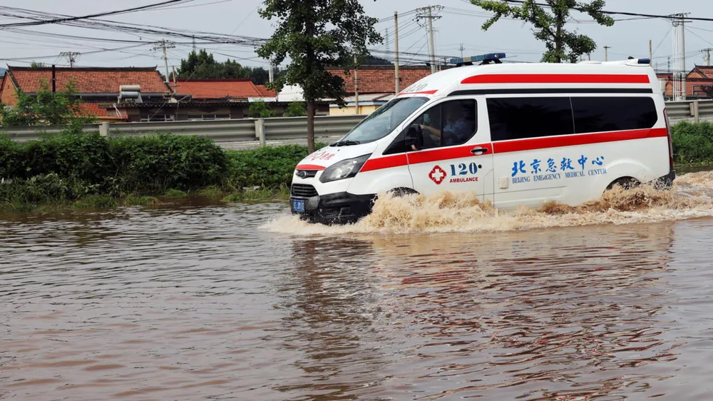 Xe cứu thương chạy qua vùng nước lũ sau khi trận mưa lớn gây ngập lụt khu vực quận Miyun, Bắc Kinh