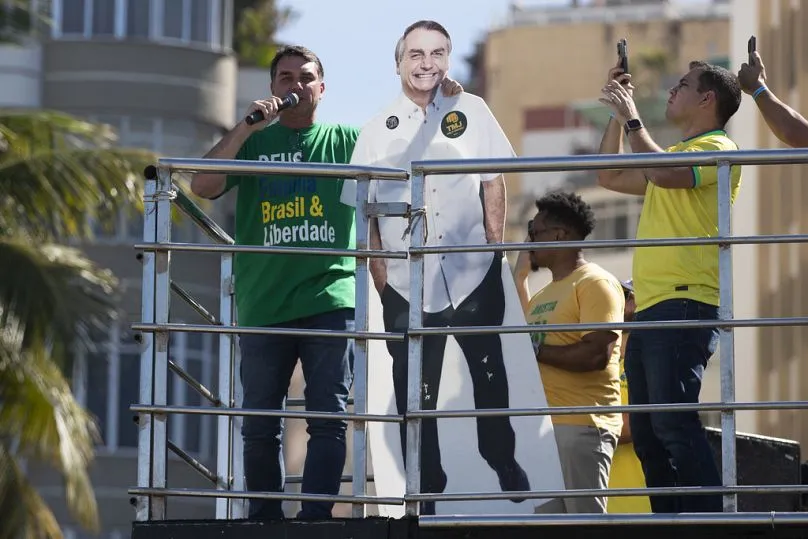 Thượng nghị sĩ Flavio Bolsonaro phát biểu trong khi ôm bức tượng cắt dán hình cha mình, cựu Tổng thống Jair Bolsonaro trong một cuộc biểu tình tại Rio de Janeiro, ngày 3-8. Thượng nghị sĩ Flavio Bolsonaro phát biểu trong khi ôm bức tượng cắt dán hình cha mình, cựu Tổng thống Jair Bolsonaro trong một cuộc biểu tình tại Rio de Janeiro, ngày 3-8.